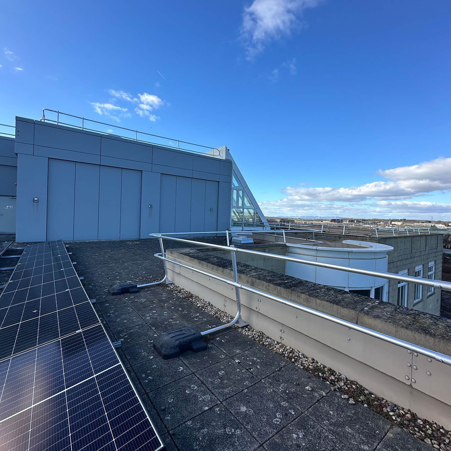 Rooftop guardrail installation beside solar panels.